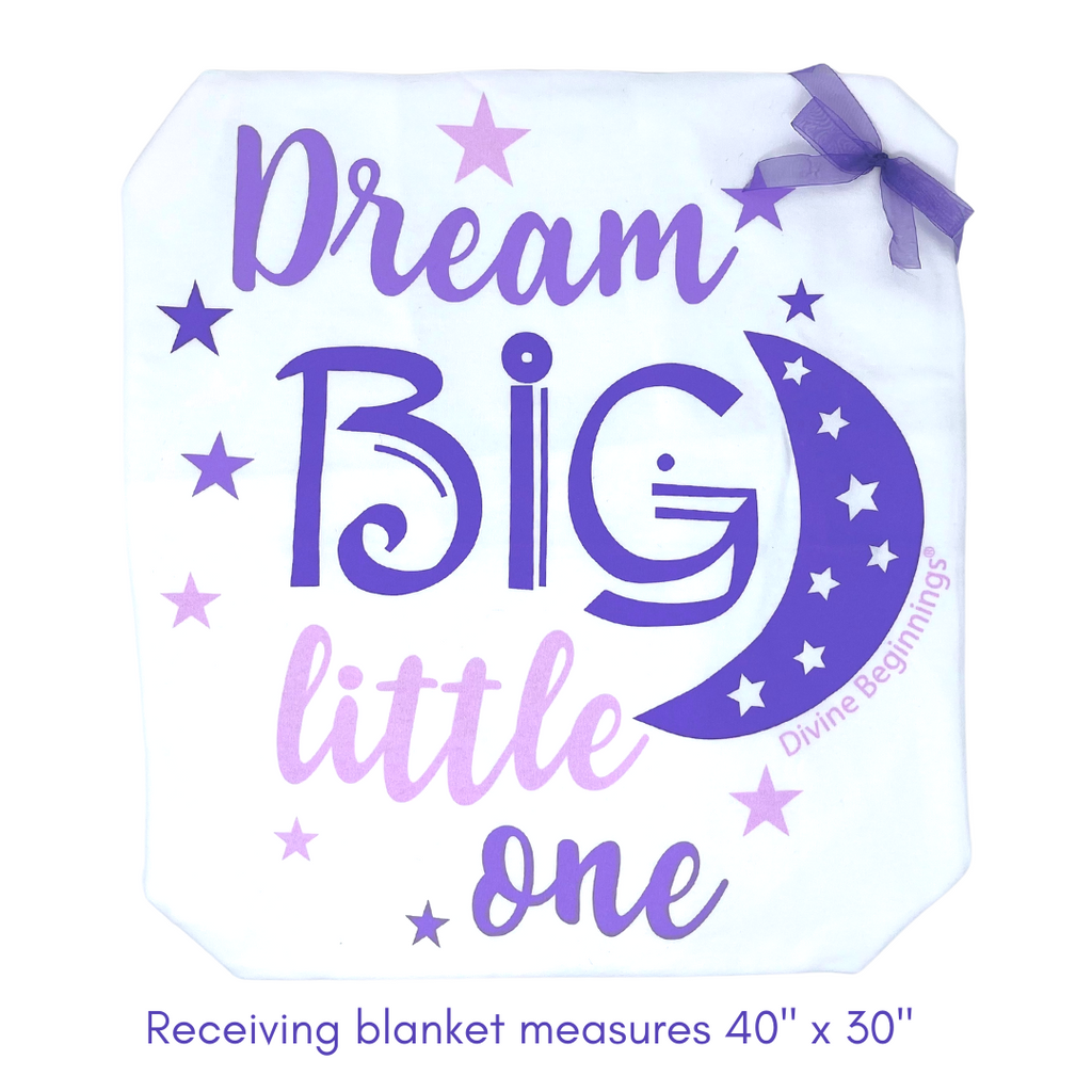 A white receiving blanket with the text 'DREAM BIG LITTLE ONE' in purple, along with a crescent moon and stars graphic.